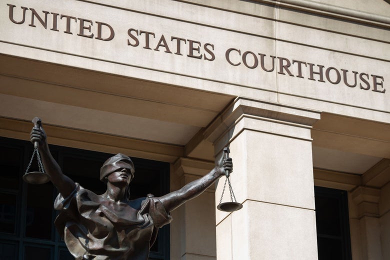 A blind-justice-holding-scales statue in front of a UNITED STATES FEDERAL COURTHOUSE sign.